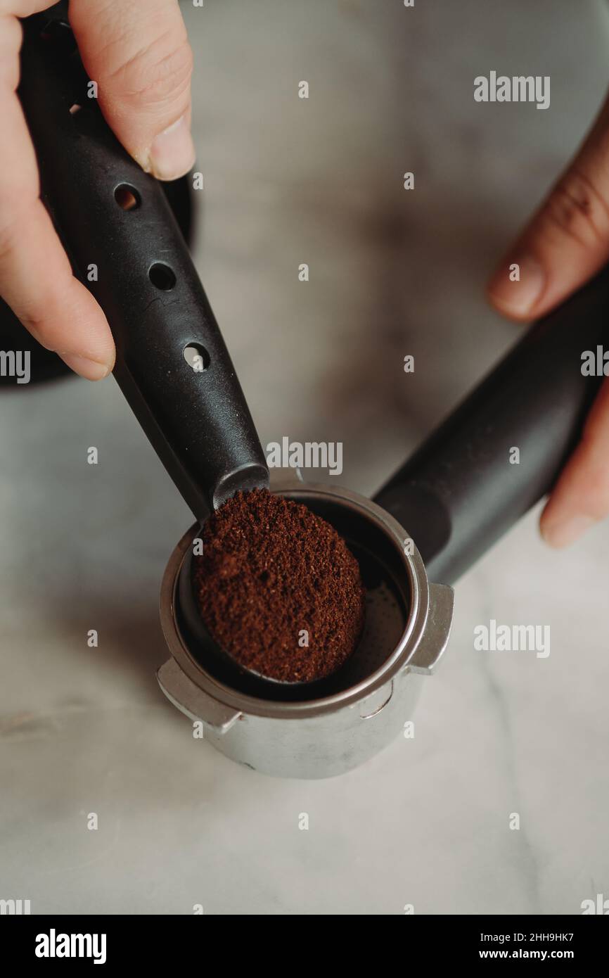 Tamping Coffee Grounds into Espresso Portafilter Against White