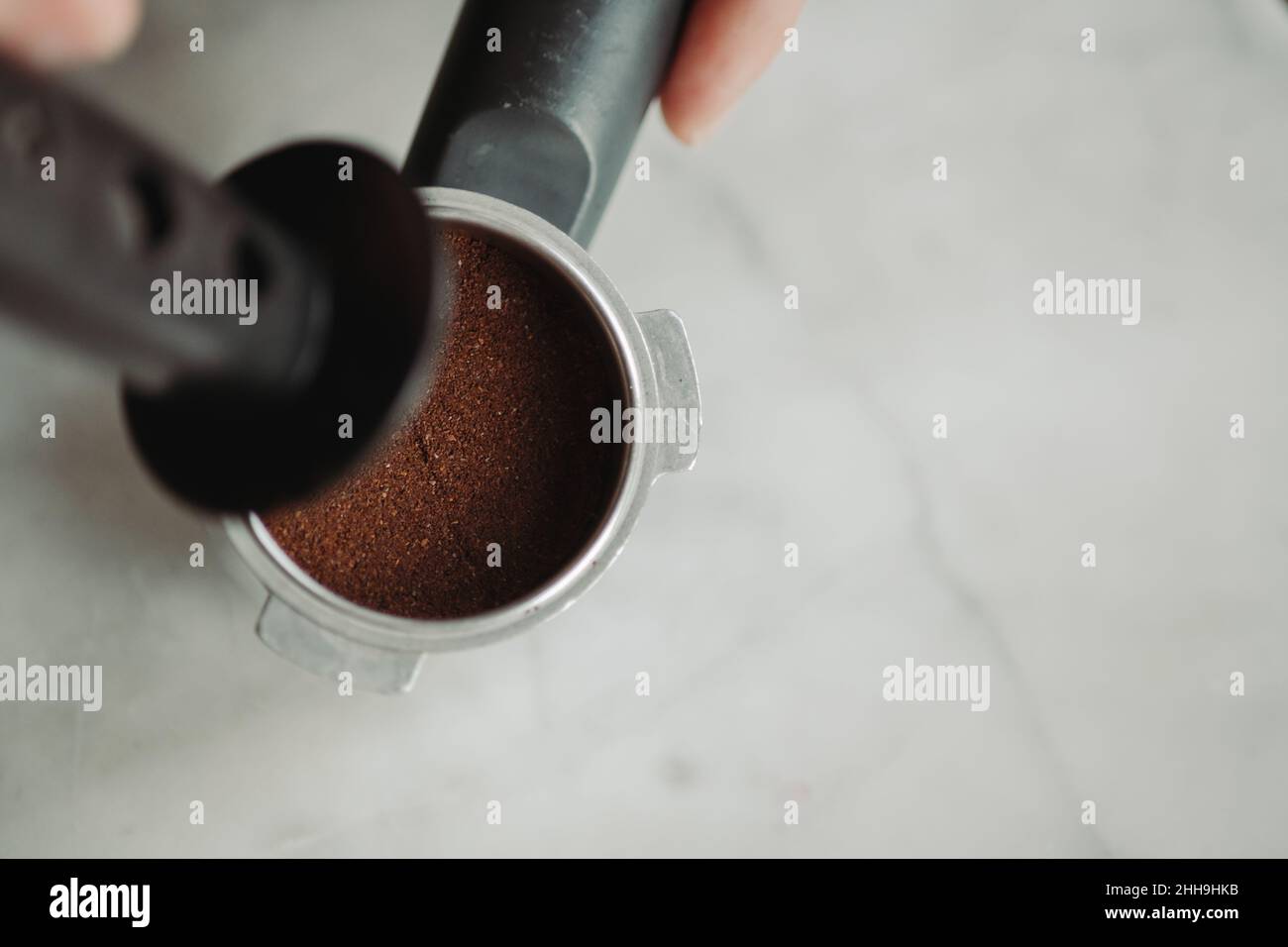 Tamping Coffee Grounds into Espresso Portafilter Against White