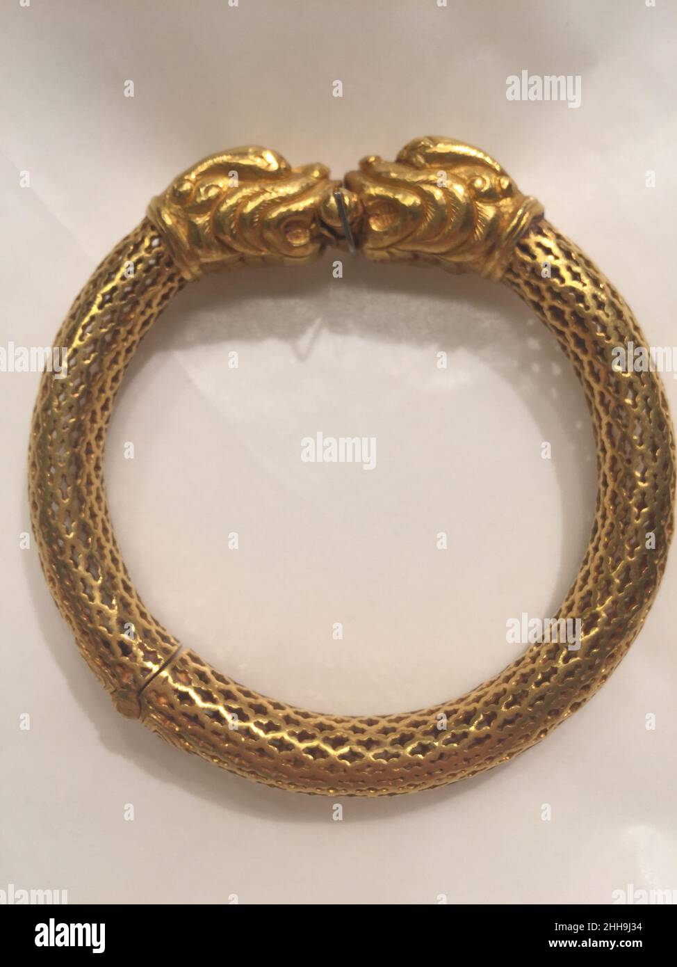 Bracelet, One of a Pair 18th century This gold bracelet is one of pair (along with 15.95.33) and has been fabricated in openwork gold, and culminates with two facing Makara or dragon heads, which also serve as its clasp. Small metal pellets within the bracelet jingle when it is moved, adding a musical quality to the beauty of the piece. Such sonorous jewels are sometimes known as jhanjhan. The hinge of this bracelet is inscribed with the Chinese Shou character (longetivity) in flattened wire.. Bracelet, One of a Pair. 18th century. Gold. Attributed to India. Jewelry Stock Photo