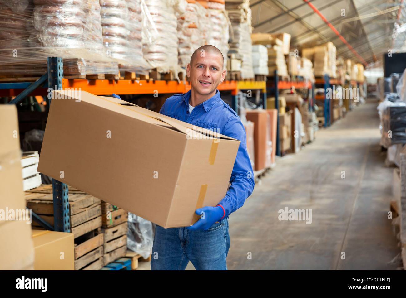 Portrait of loader with a large box in his hands in store warehouse ...