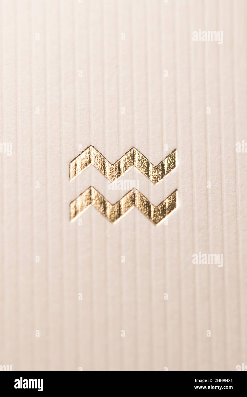 Close up horoscope sign of the zodiac symbol in gold leaf representing the constellation of Aquarius Stock Photo