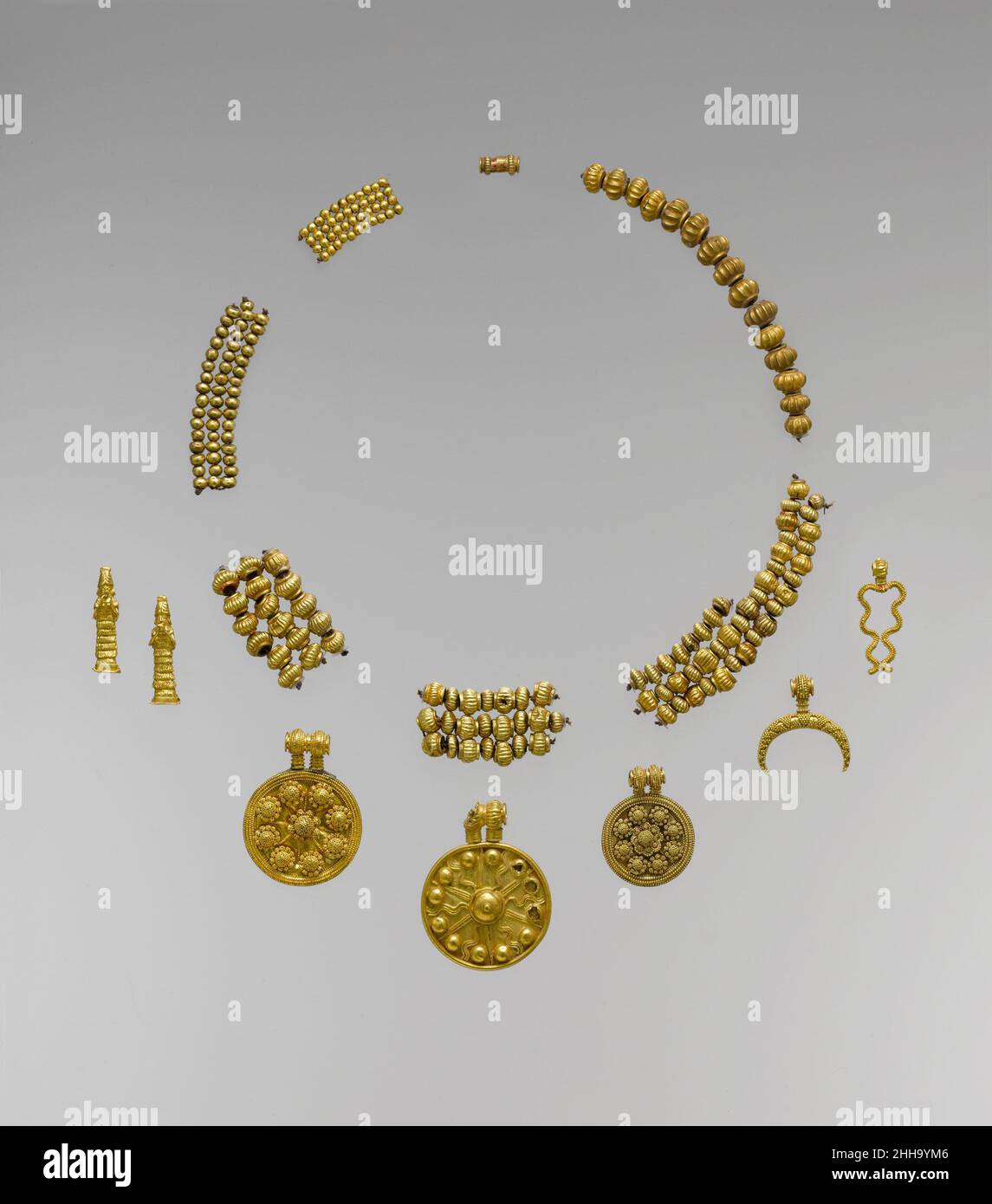 Necklace pendants and beads ca. 18th–17th century B.C. Babylonian These gold pendants and beads exemplify the finest craftsmanship in gold from the ancient Near East, and each represents a deity or the symbol of a deity. The two female figures, wearing horned headdresses and long flounced dresses, probably represent Lama, a protective goddess; the disk with rays emanating from a central boss represents Shamash, the sun god; and the forked lightning is the symbol for Adad, the storm god. The two disks with granulated rosettes may be symbols of Ishtar, goddess of love and war represented by the Stock Photo