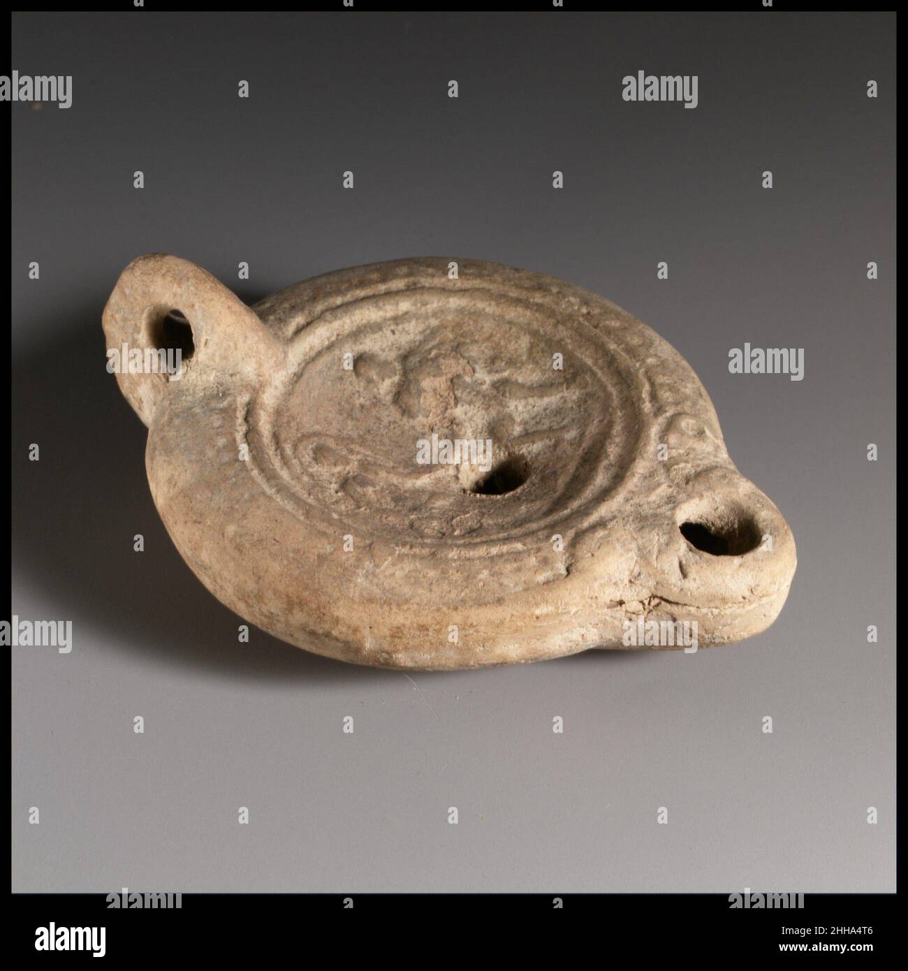 Terracotta oil lamp 2nd century A.D. Roman Loeschcke Type 8; ring handle.  Mold-made. Discus: to right, standing male figure and, to left, female  standing figure with veil over her head, holding hands.