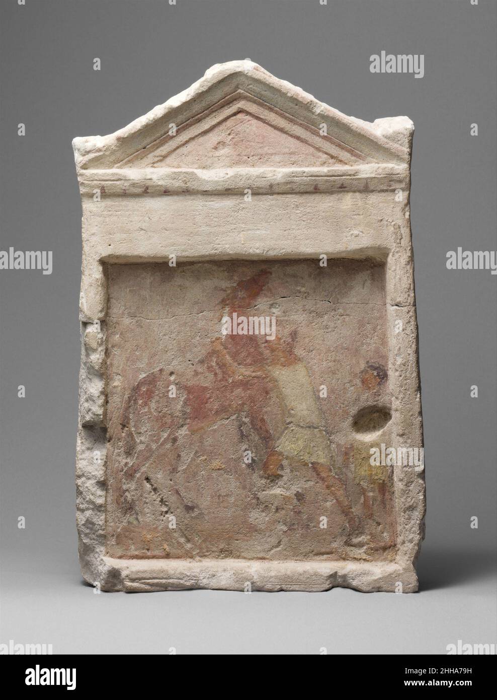 Painted limestone funerary slab with a man controlling a rearing horse 2nd half of 3rd century B.C. Greek During the Ptolemaic period a distinctive type of subterranean tomb for multiple burials proliferated in the cemeteries around the city of Alexandria. Underground chambers cut into the living rock radiated from a central courtyard open to the sky. Most chambers contained a number of loculi, long narrow niches cut into the walls, which served as burial slots. Some loculi were sealed with painted limestone slabs in the form of small shrines. Here, a lively depiction of a man trying to bridle Stock Photo
