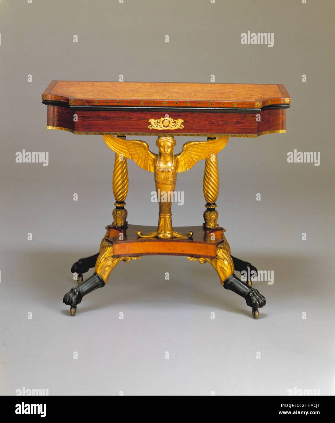 Card Table 1810–19 Attributed to Charles-Honoré Lannuier Although it does not bear Lannuier’s label, this table is nearly identical to six pairs of tables and three single tables that do. It demonstrates Lannuier’s skillful combination of French influences. The gilded, winged caryatid and the hocked animal legs are reminiscent of illustrations in Pierre de La Mésangère’s 'Collection de meubles et objets de gout' (1802–35), which includes motifs often found in Lannuier’s work.. Card Table  1444 Stock Photo