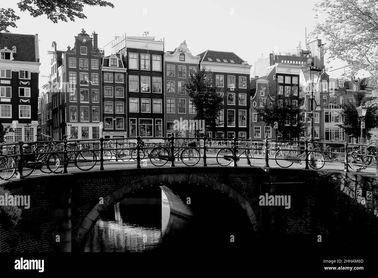 Black and white photograph of a canal, bridge, bicycles and historic buildings, West Canal Ring, Amsterdam, Holland, Europe, 2016. Stock Photo