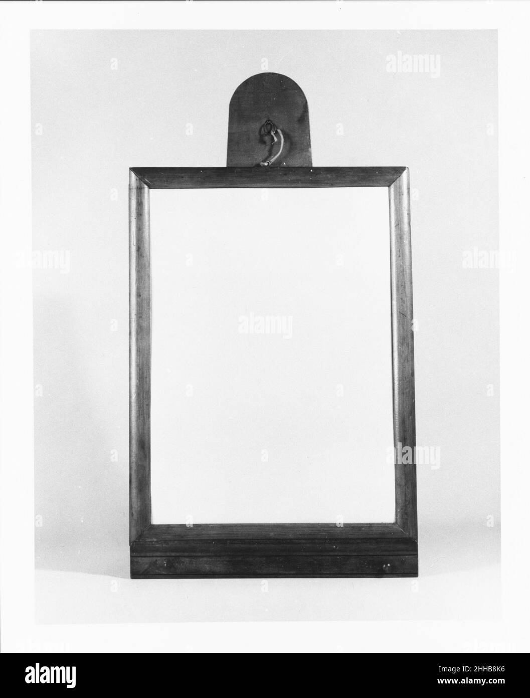 Looking Glass 1840–60 United Society of Believers in Christ’s Second Appearing (“Shakers”), Mount Lebanon, New York The earliest Shaker mirrors were made after 1821, when the religious laws allowing their use were written. This example with a convex-molded frame, and T-shape wall bracket. The brass knobs on the base would have been used to suspend brushes and combs.. Looking Glass  4868 Stock Photo