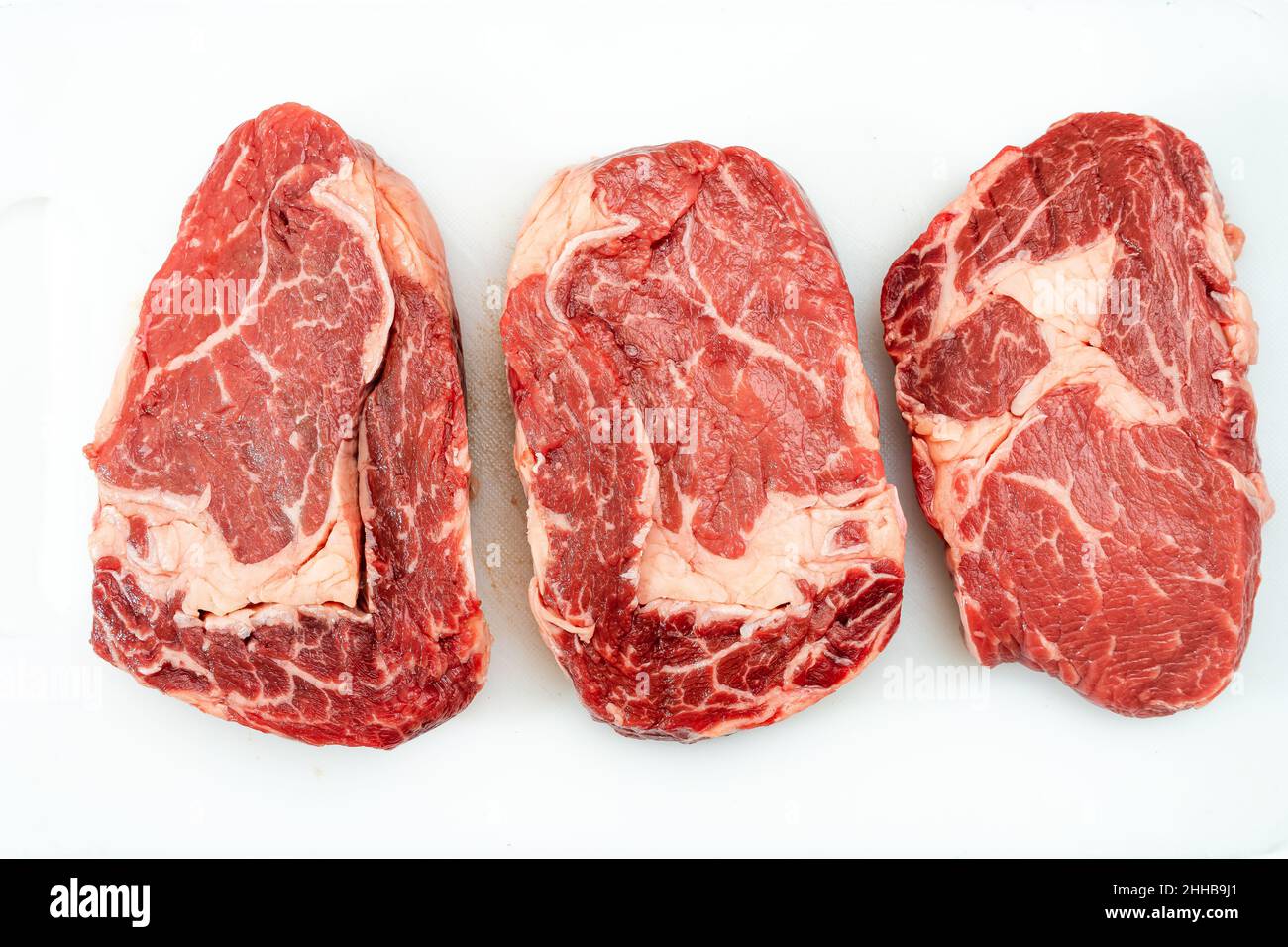three raw Rib eye steaks on a white background. Food concept. overhead view. Stock Photo