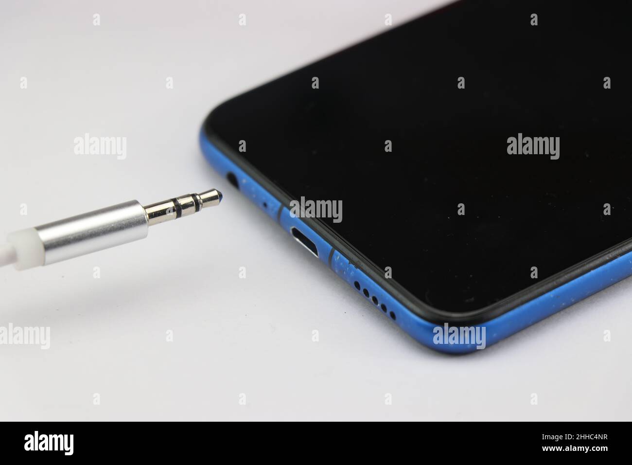 Connection of 3.5mm audio jack to a mobile phone on white background. Music concept Stock Photo