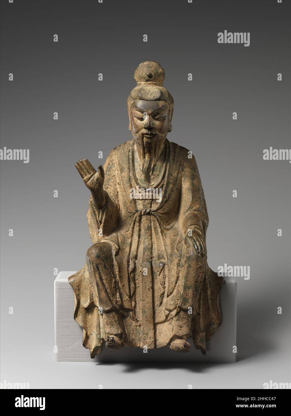 Daoist Immortal, probably Laozi (??) 10th century China This sculpture epitomizes the merging of religious and secular imagery in later Chinese Buddhist sculpture. With his shaven head and elongated earlobes, the figure resembles a luohan (one of the Indian disciples of the Buddha), but his refined facial features, dignified posture, long-sleeved robe, and pointed shoes—all attributes associated with Confucian scholar-officials—identify him unmistakably as a youthful monk.The sculpture’s tendency toward abstraction and stylization—the contours of the head, body, and robes are conveyed through Stock Photo