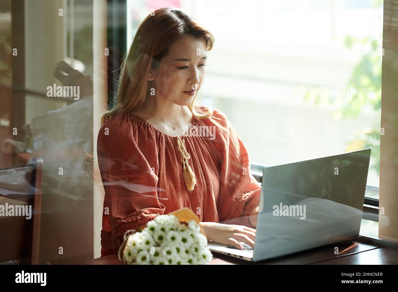 Young woman concentrated on working on laptop and checking her programming code Stock Photo