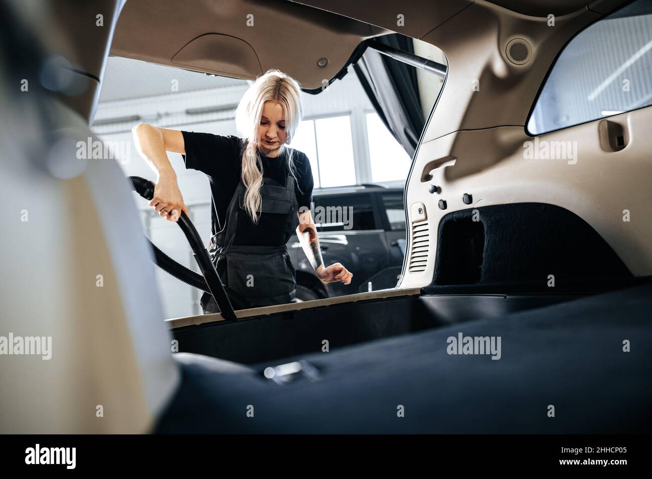 Worker woman vacuum cleaning dust interior inside car in car wash Stock