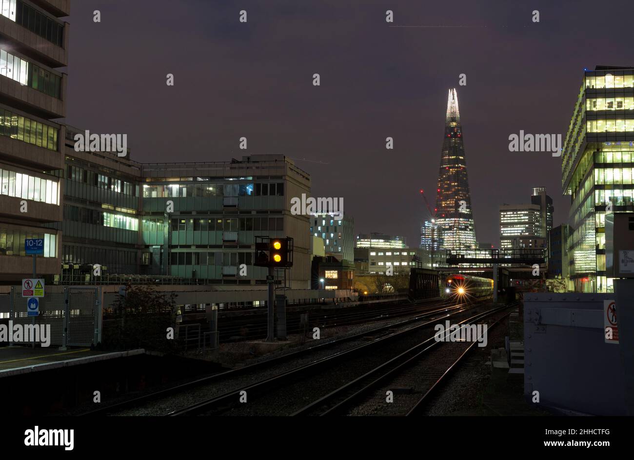 South Eastern Trains class 465 approaching London Waterloo east at night with the Shard lit up and a yellow railway signal Stock Photo