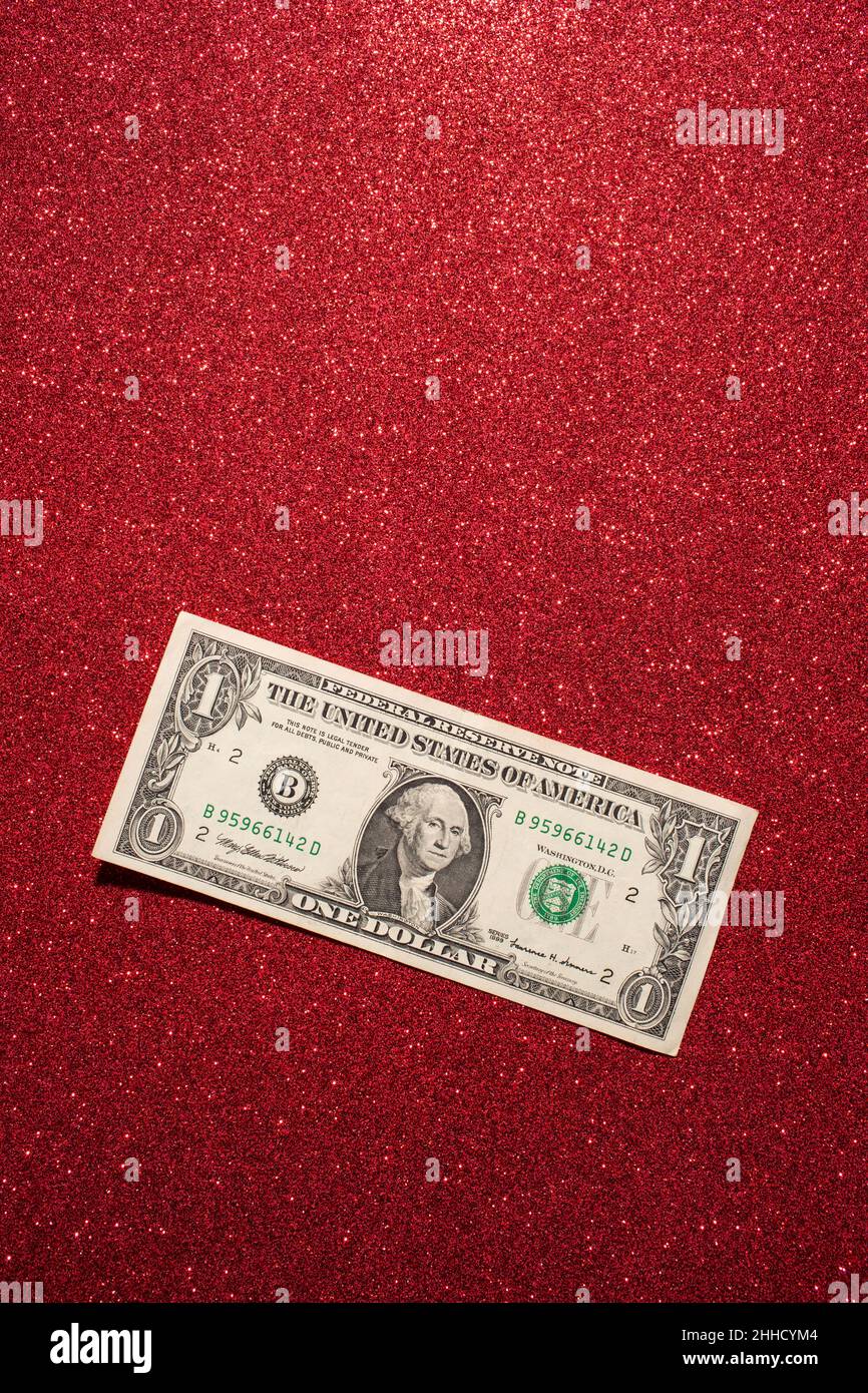 High angle view of one US dollar bill on red glittering background Stock Photo