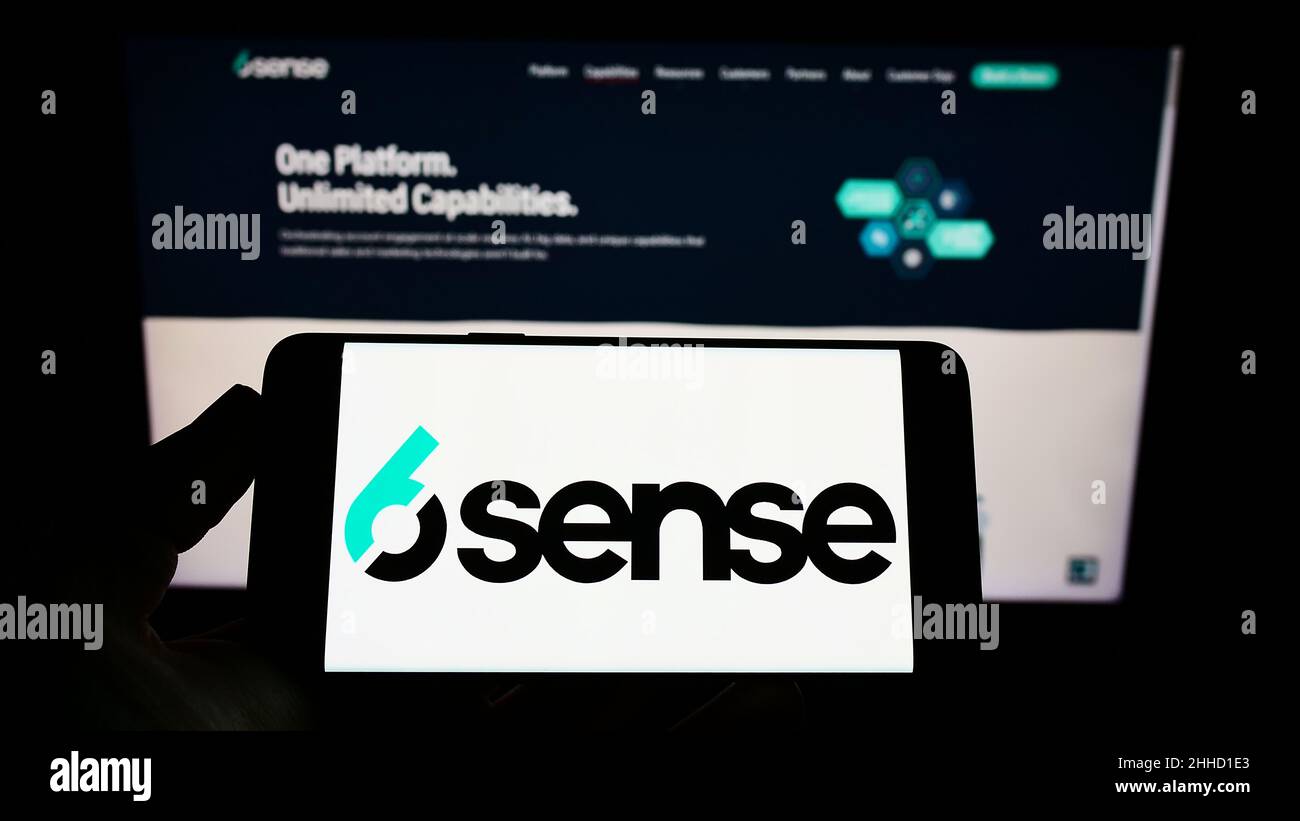 Person holding cellphone with logo of US software company 6Sense Insights Inc. on screen in front of business webpage. Focus on phone display. Stock Photo