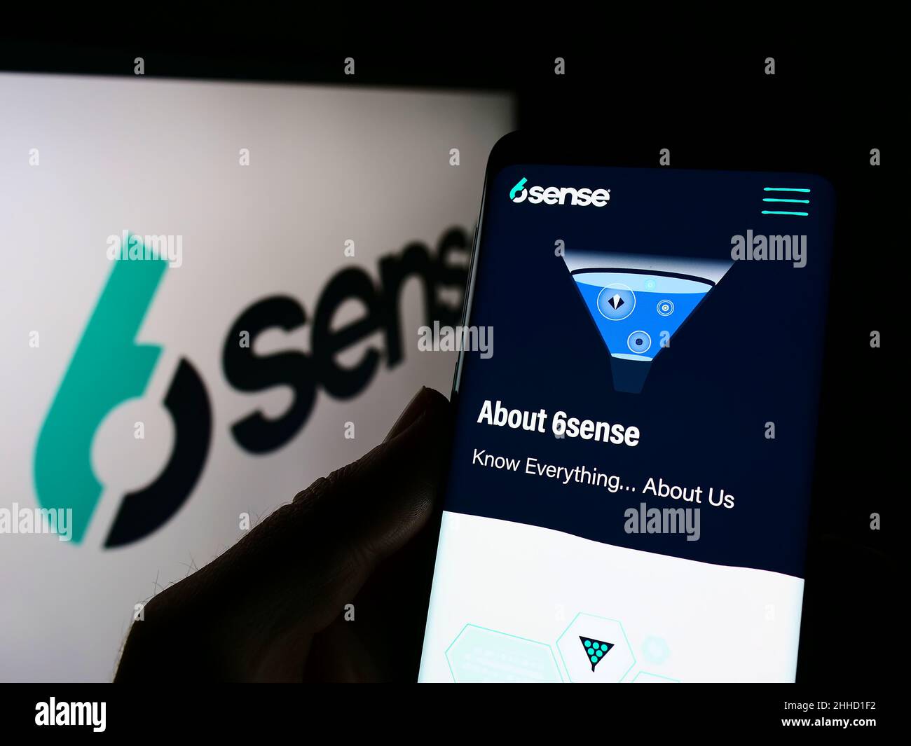 Person holding cellphone with website of US software company 6Sense Insights Inc. on screen in front of logo. Focus on center of phone display. Stock Photo