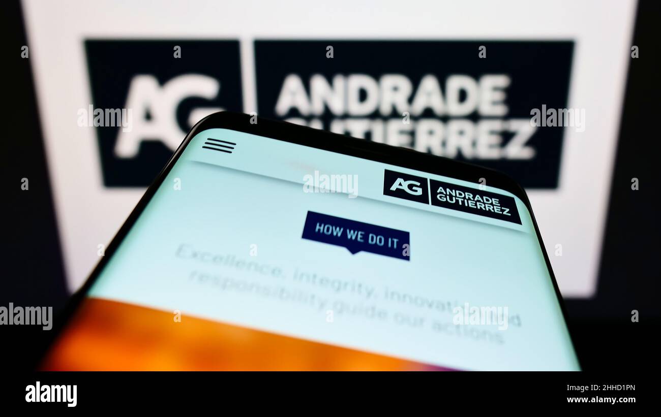 Mobile phone with webpage of Brazilian conglomerate Andrade Gutierrez S.A. on screen in front of company logo. Focus on top-left of phone display. Stock Photo