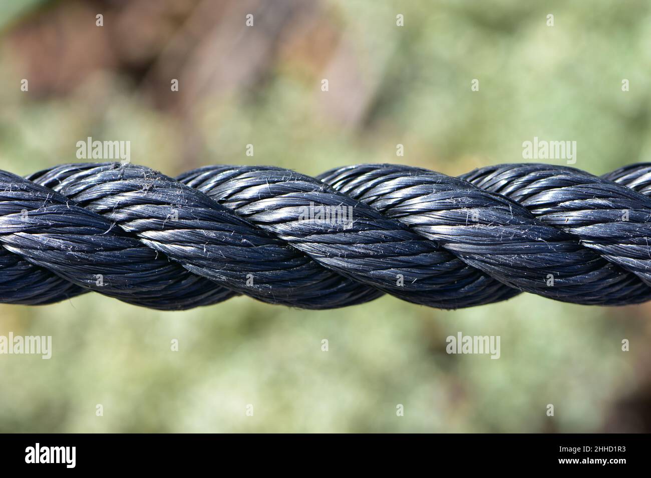 Detail of thick black twisted synthetic rope with some surface fibres worn by abrasion. Stock Photo