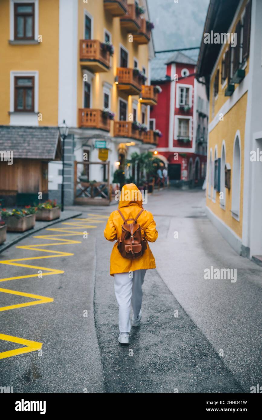 woman in yellow raincoat walking by hallstatt streets rainy weather ...
