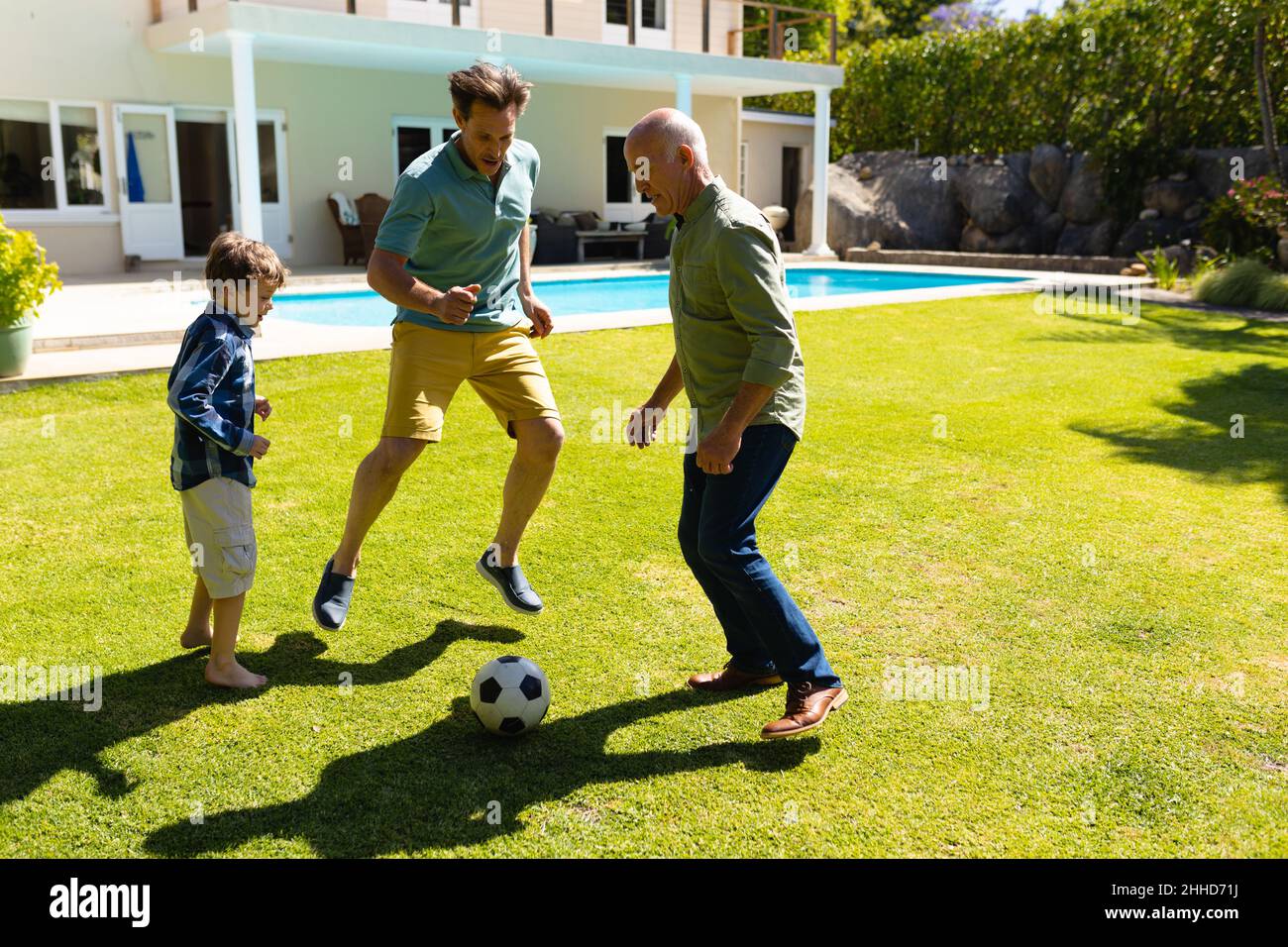 Caucasian grandfather, father and son playing football together in the garden Stock Photo