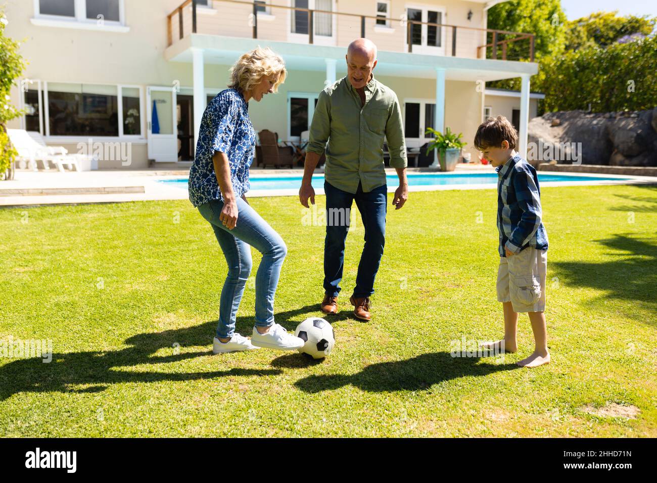 Caucasian grandparents and grandson playing football together in the garden Stock Photo