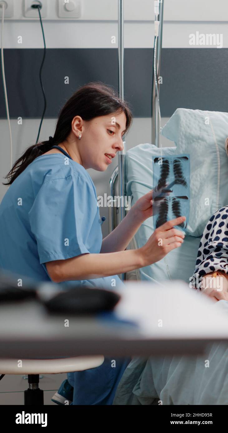 Medical assistant pointing at x ray scan for senior woman with illness ...