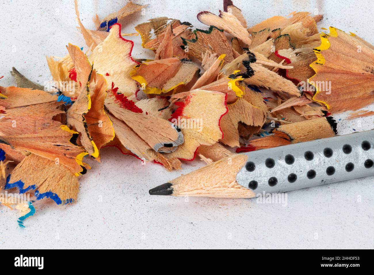 Sharpened black pencil with colored sharp waste on a white background Stock Photo