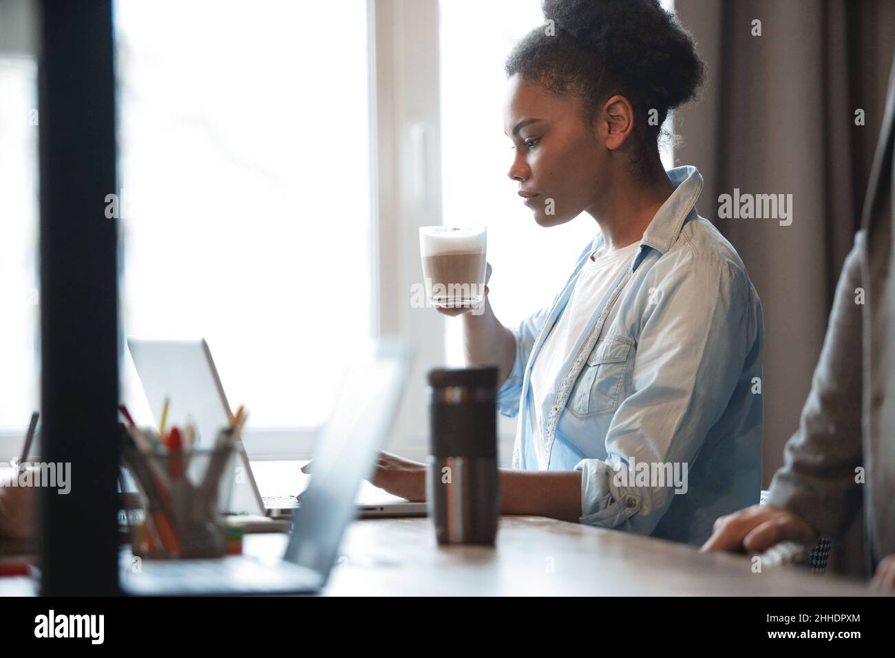 Beautiful woman having a morning coffee at her desk in the office ...