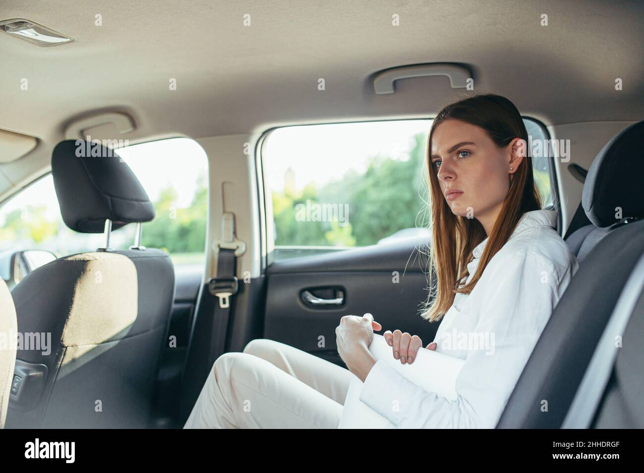 Tired female car passenger holding laptop in hands Stock Photo