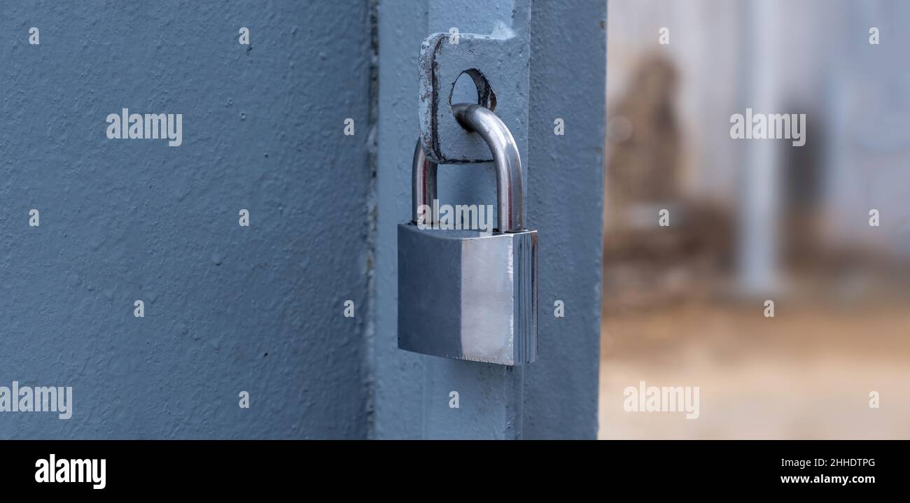 Heavy metal padlock on an open entrance gate, closeup view, banner. Stock Photo