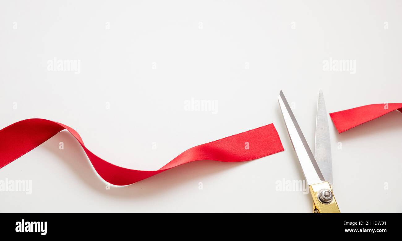 Grand opening, ribbon cut, Gold scissors cutting red satin ribbon isolated on white background. Inaugural invitation, business launch concept, copy sp Stock Photo