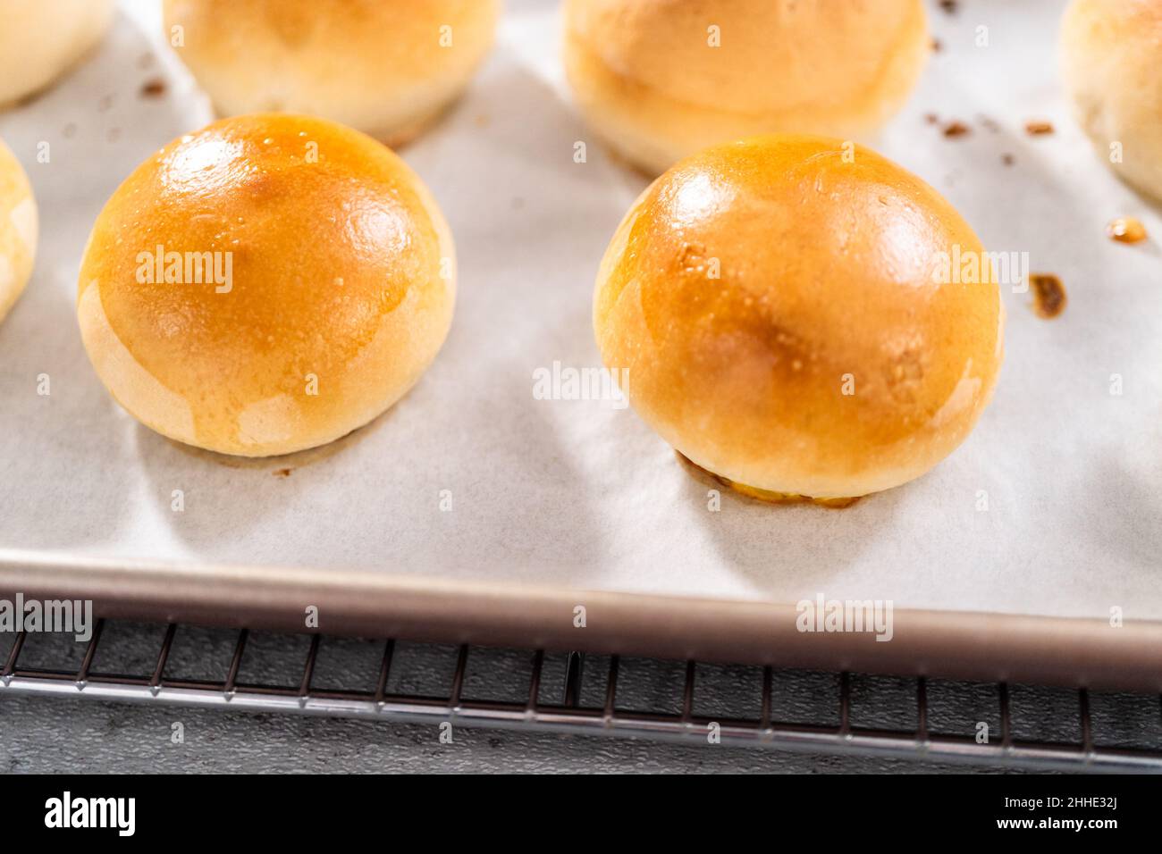 Freshly baked dinner rolls with an egg wash on a baking sheet lined