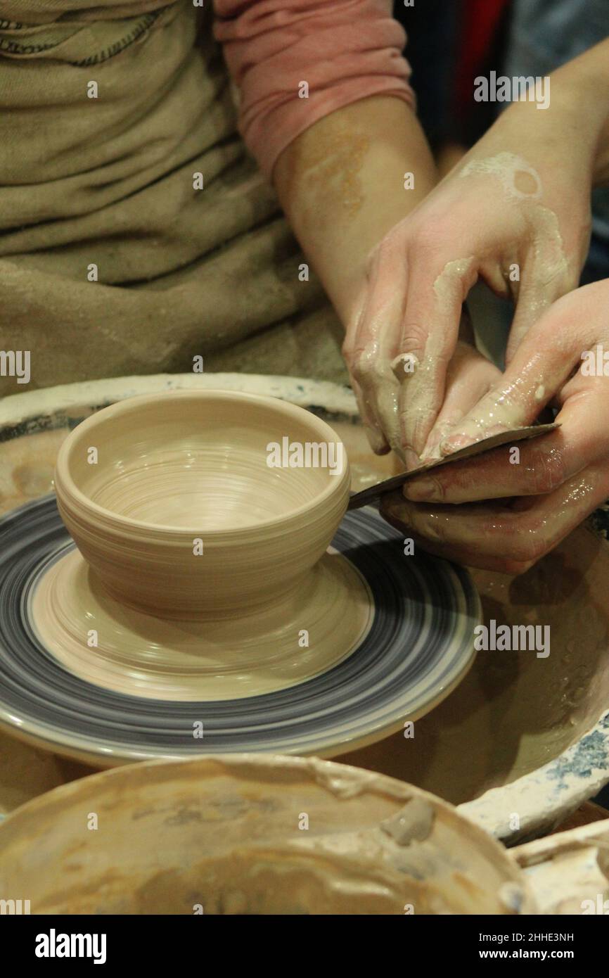 Pottery. Sculpt dishes from clay. Modeling of pots. Dirty hands of the master close-up in clay. Hobby Stock Photo