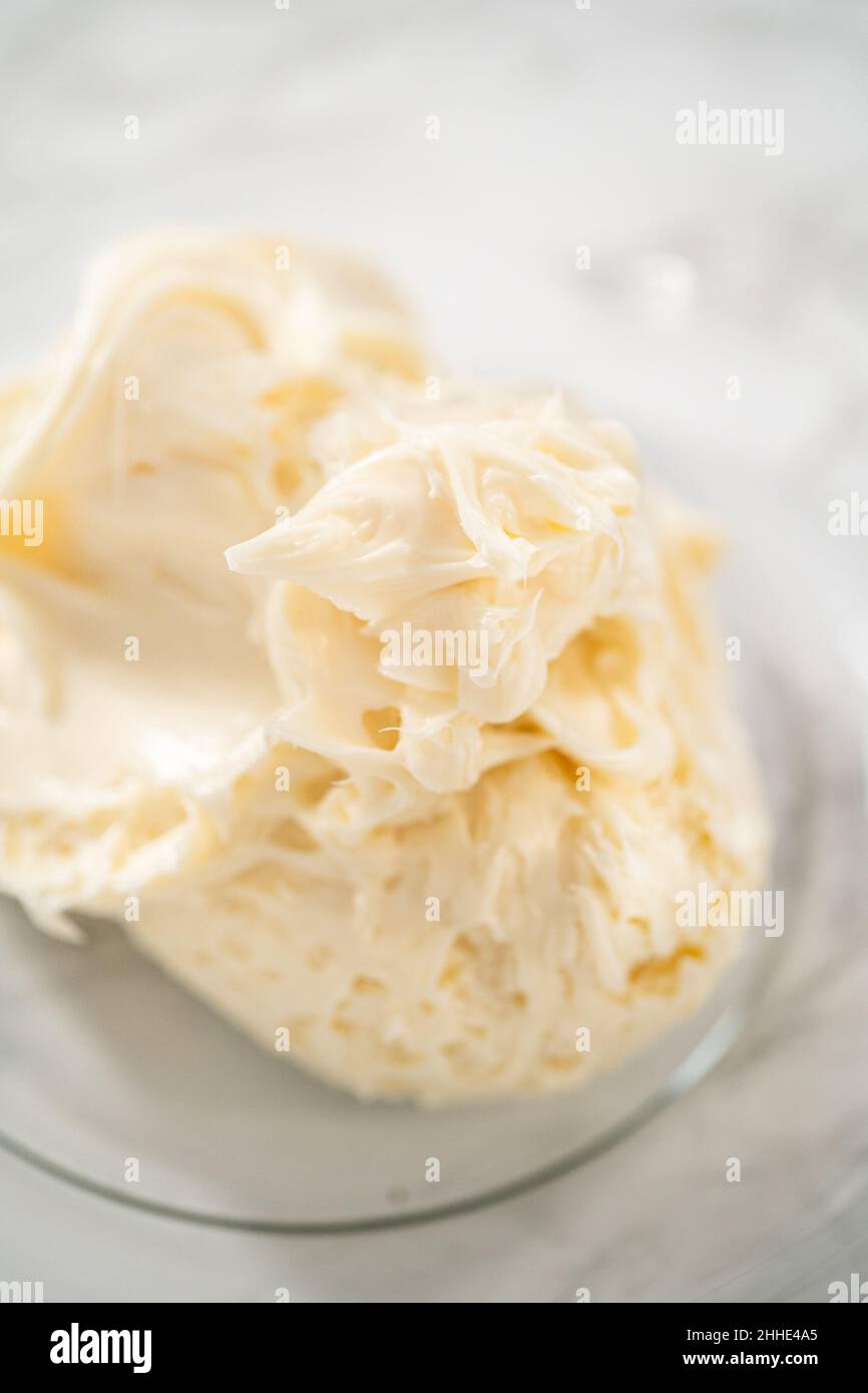 Whisking buttercream frosting in a glass mixing bowl with an electric