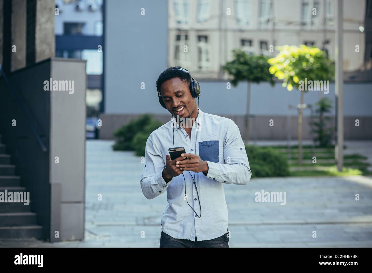 Man listening to music uses big headphones, walks down the street, happy african american Stock Photo