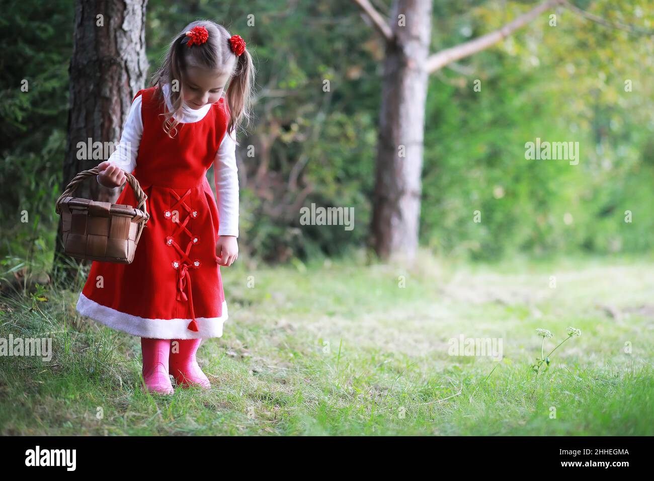 A little girl in a red hat and dresses is walking in the park. Cosplay ...