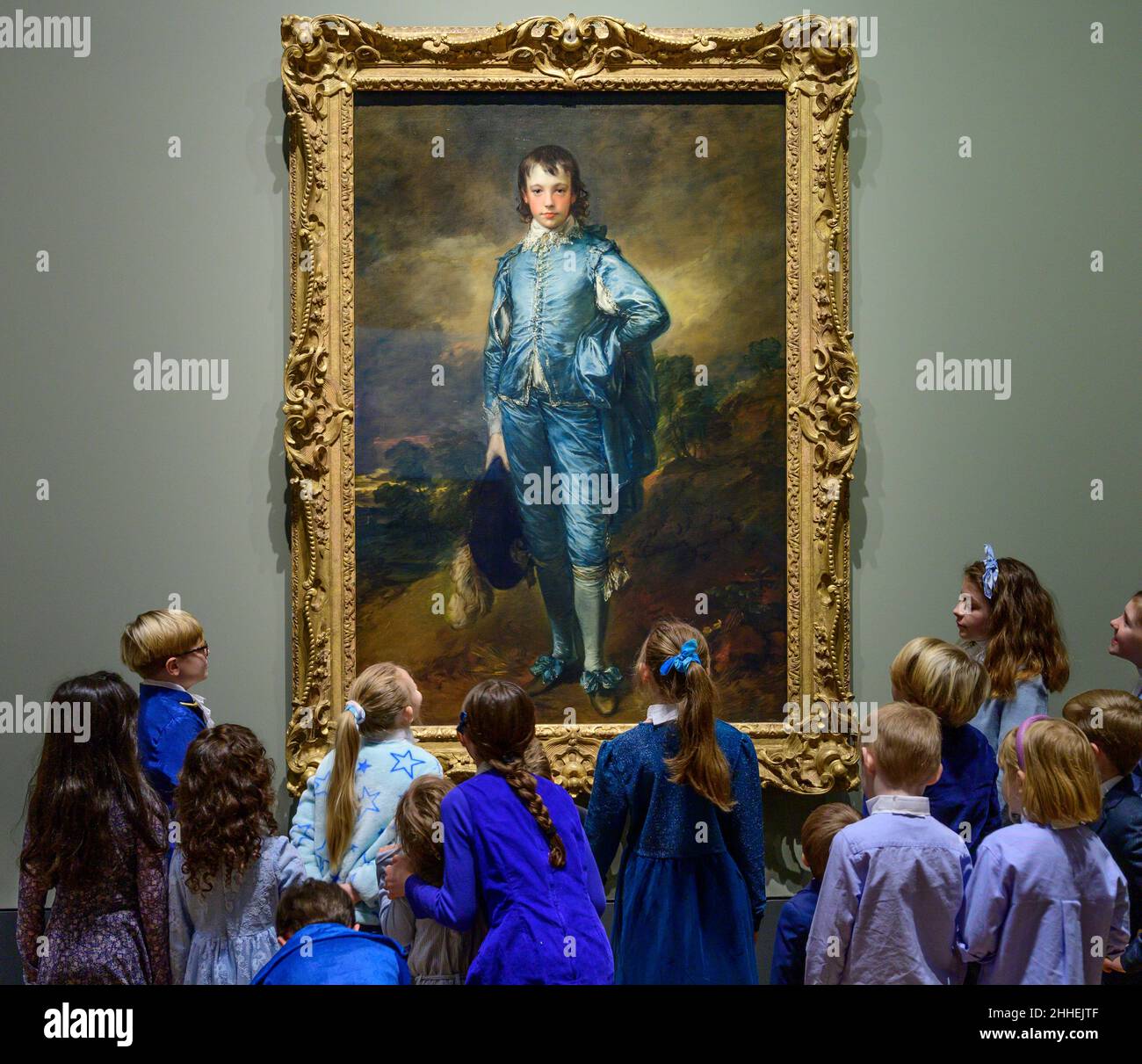 The National Gallery, London, UK. 24 January 2022. ‘The Blue Boy’, 1770, by Thomas Gainsborough goes on display at the National Gallery on the 100th anniversary of its last presentation in the UK. The work is now owned by the Huntington Library, Art Museum, and Botanical Gardens in San Marino, California where it has been on display for the past century. A group of ‘blue boys’, children of National Gallery staff and of the US Embassy in London, pose in front of the painting, all dressed in shades of blue with cravats to resemble the figure in the painting. Credit: Malcolm Park/Alamy Live News. Stock Photo