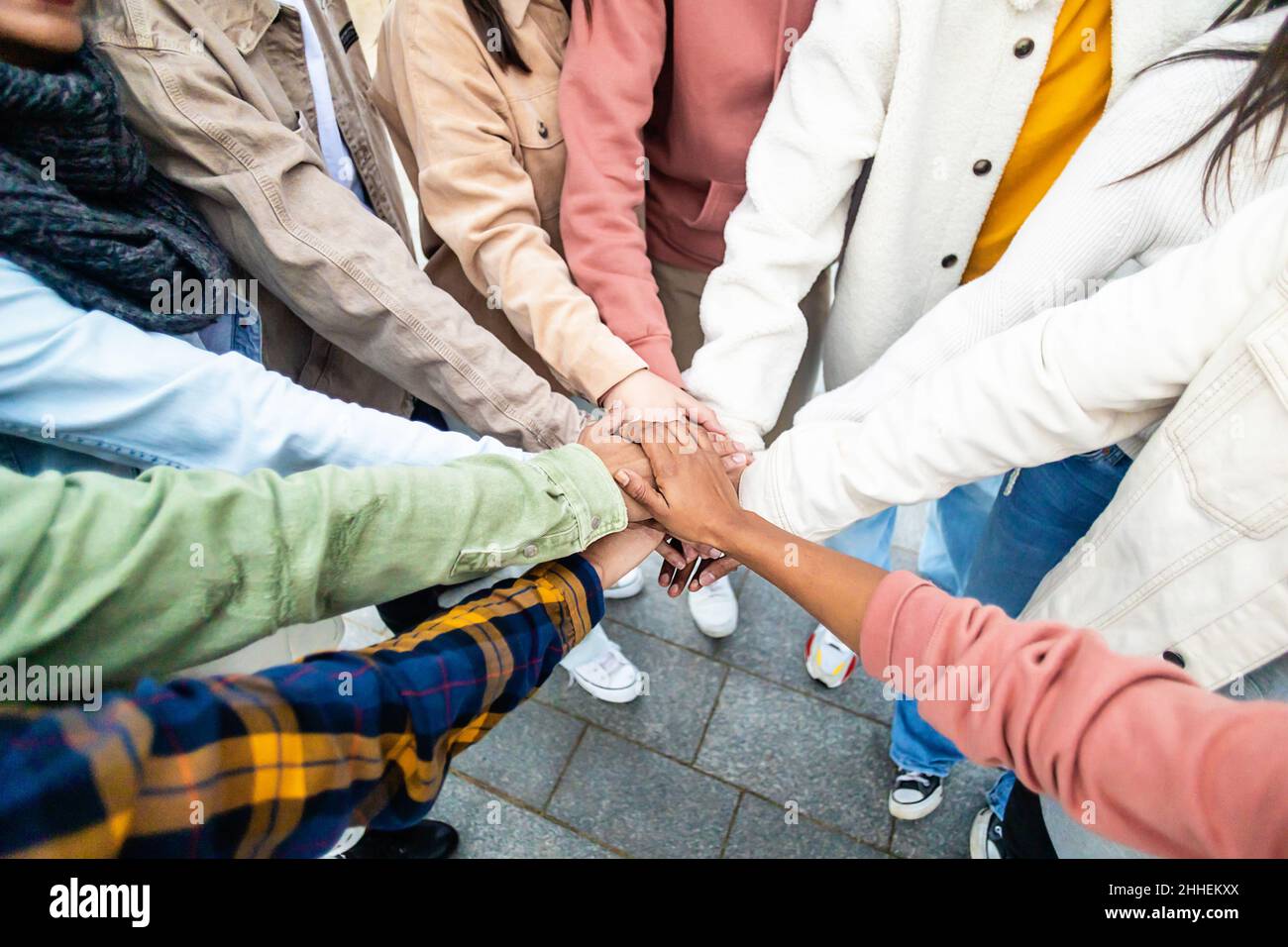 Young people stacking hands in city street Stock Photo