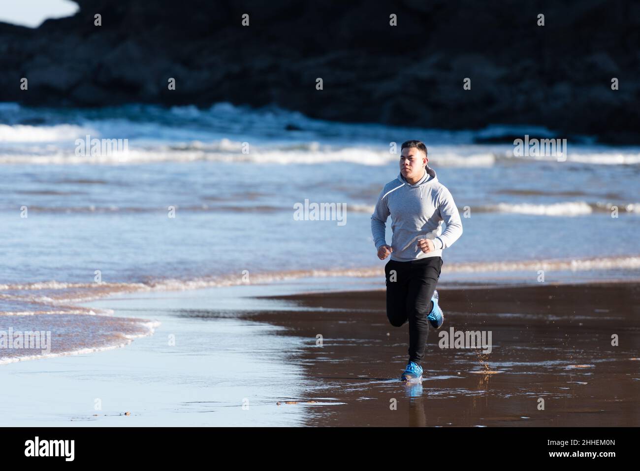 South American young man running at seaside Stock Photo