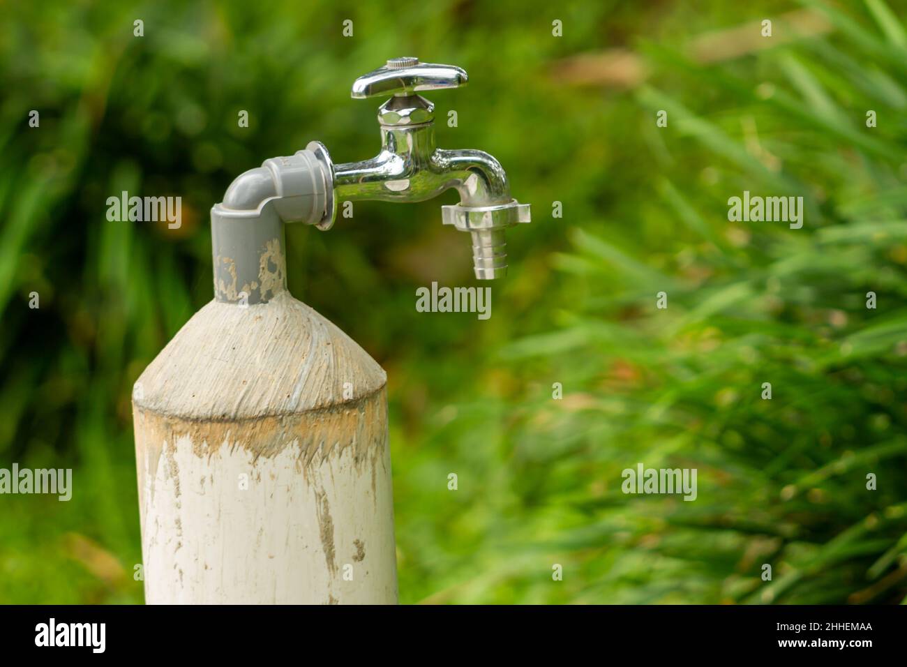 A metal water faucet is in a garden, used for washing hands, which is a basic need during the covid-19 pandemic Stock Photo