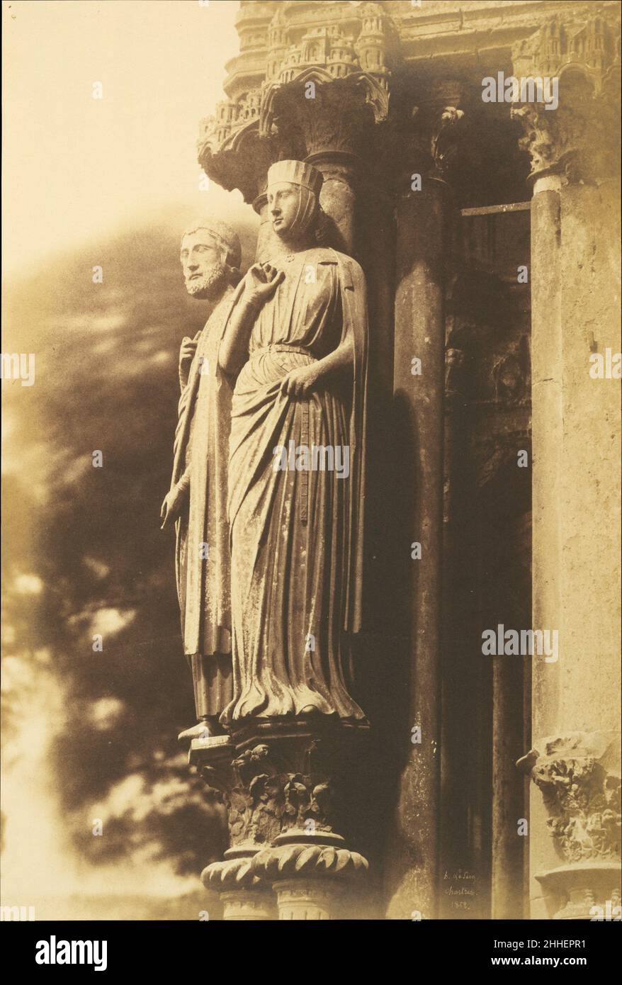 [Large Figures on the North Porch, Chartres Cathedral] 1852 Henri-Jean-Louis Le Secq French Seen obliquely from the eye level of a cathedral visitor, the portal sculptures in Henri Le Secq's photograph appear disengaged from their stone support. The figures' corporeality is animated by sharp focus and by their position between shadowed columns and a blur of moving foliage. Le Secq's inspired photography of French cathedrals won critical praise and government support, because he demonstrated the new medium's capacity to provide detailed and accurate records. This photograph, made in 1852, is al Stock Photo