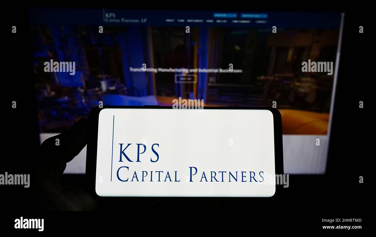 Person holding smartphone with logo of US investment company KPS Capital Partners LP on screen in front of website. Focus on phone display. Stock Photo