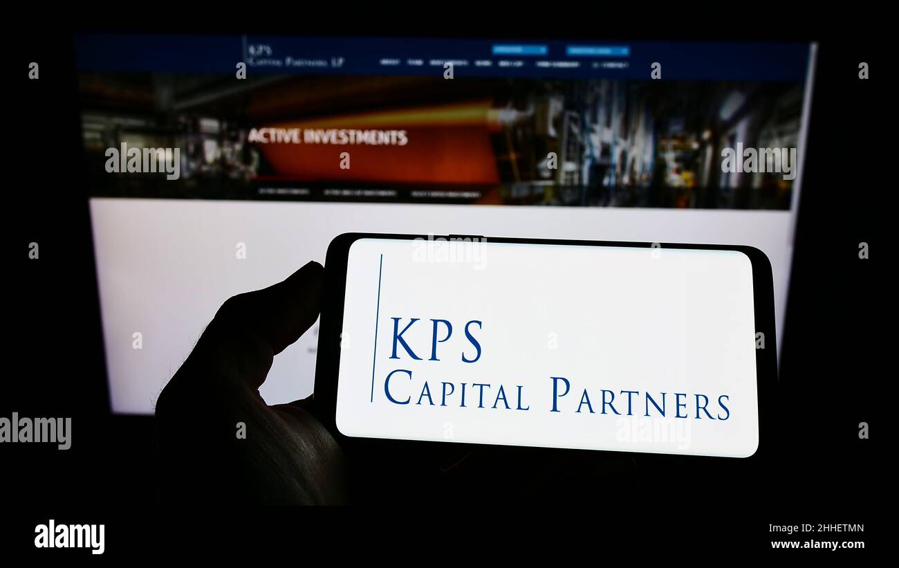 Person holding cellphone with logo of American investment company KPS Capital Partners LP on screen in front of webpage. Focus on phone display. Stock Photo