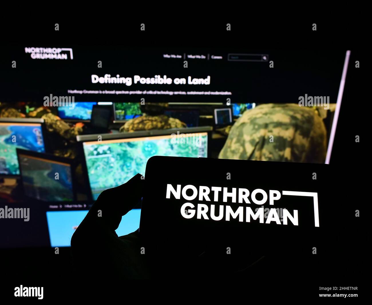 Person holding mobile phone with logo of US defense company Northrop Grumman Corporation on screen in front of web page. Focus on phone display. Stock Photo