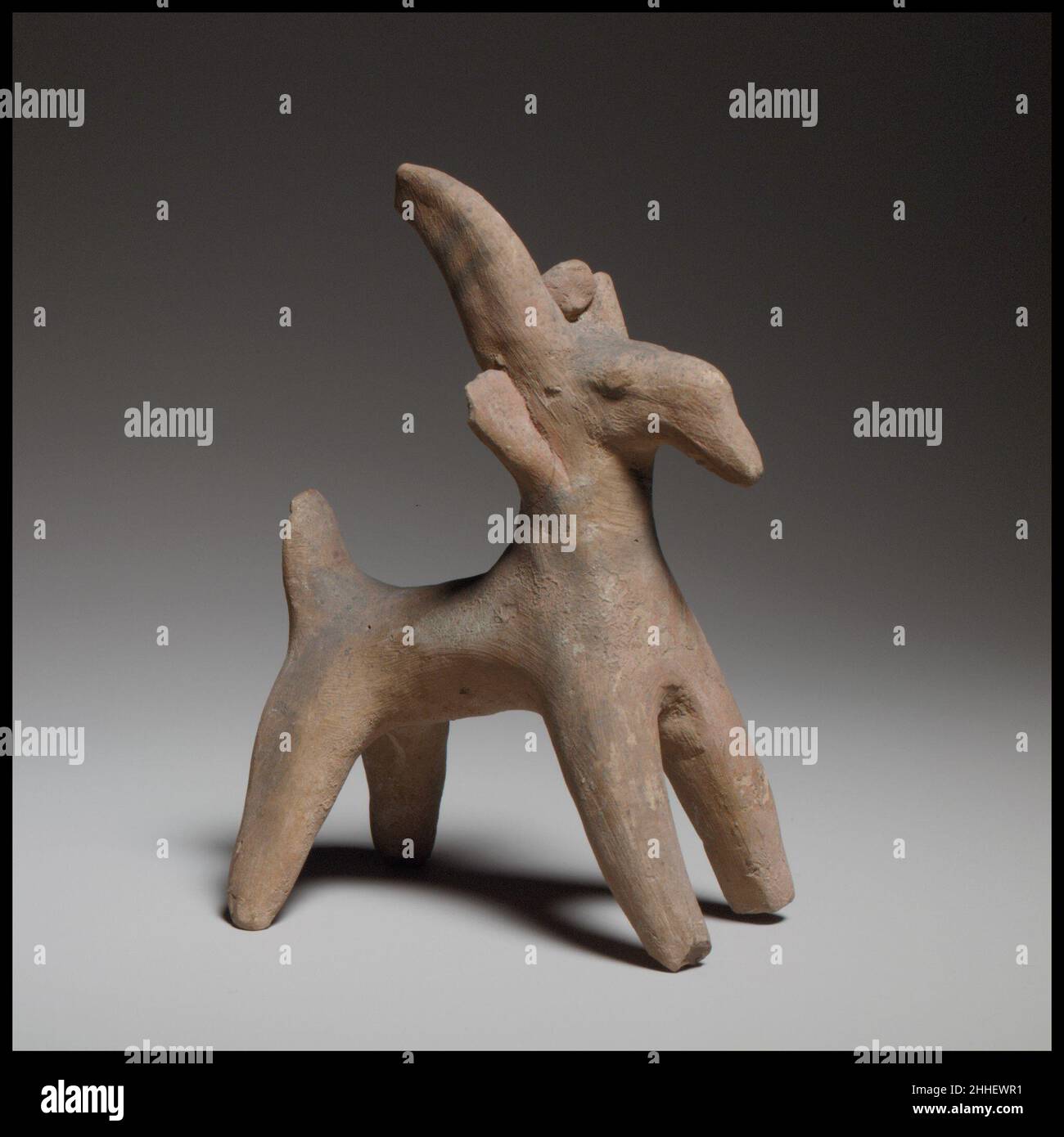 Goat figurine ca. 600–480 B.C. Cypriot The figurine is handmade and solid. It has a cylindrical body, a flat upright tail, long horns that curve backward, pellet ears, a protuberant nose, a pointed muzzle, and bulging eyes.. Goat figurine  241319 Stock Photo