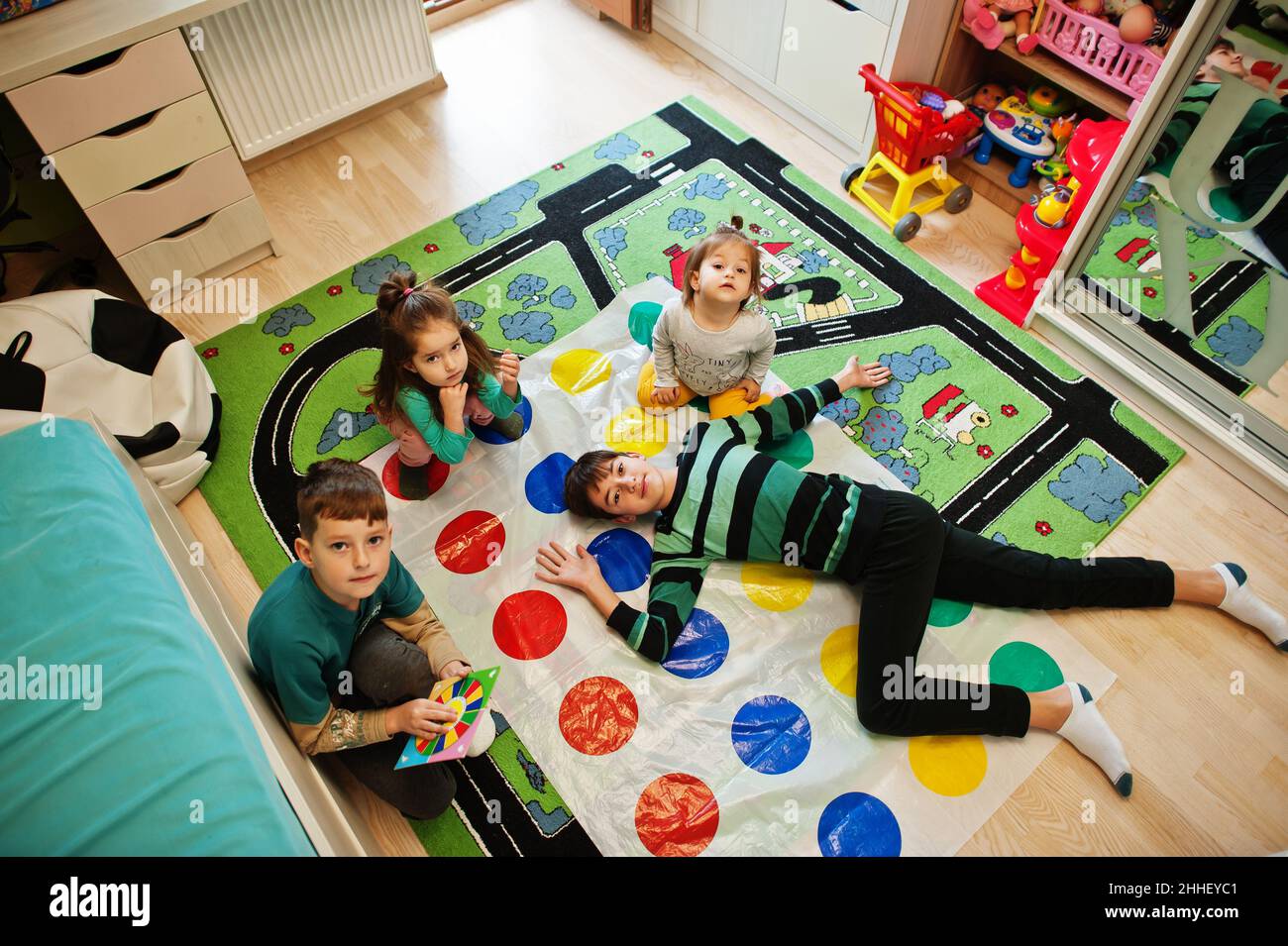 Happy family having fun together,four kids playing twister game at home. Stock Photo