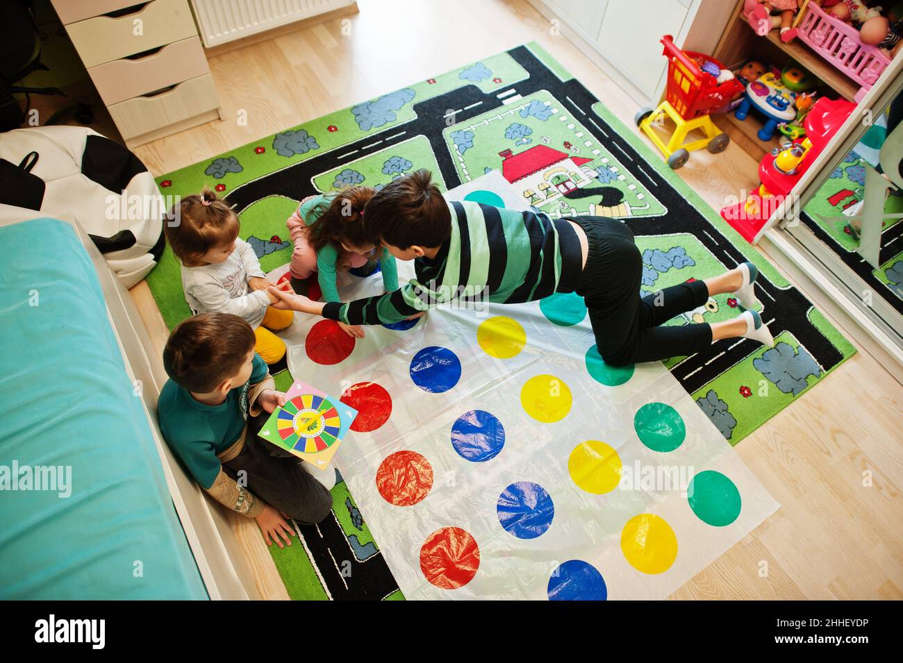 Happy family having fun together,four kids playing twister game at home. Stock Photo