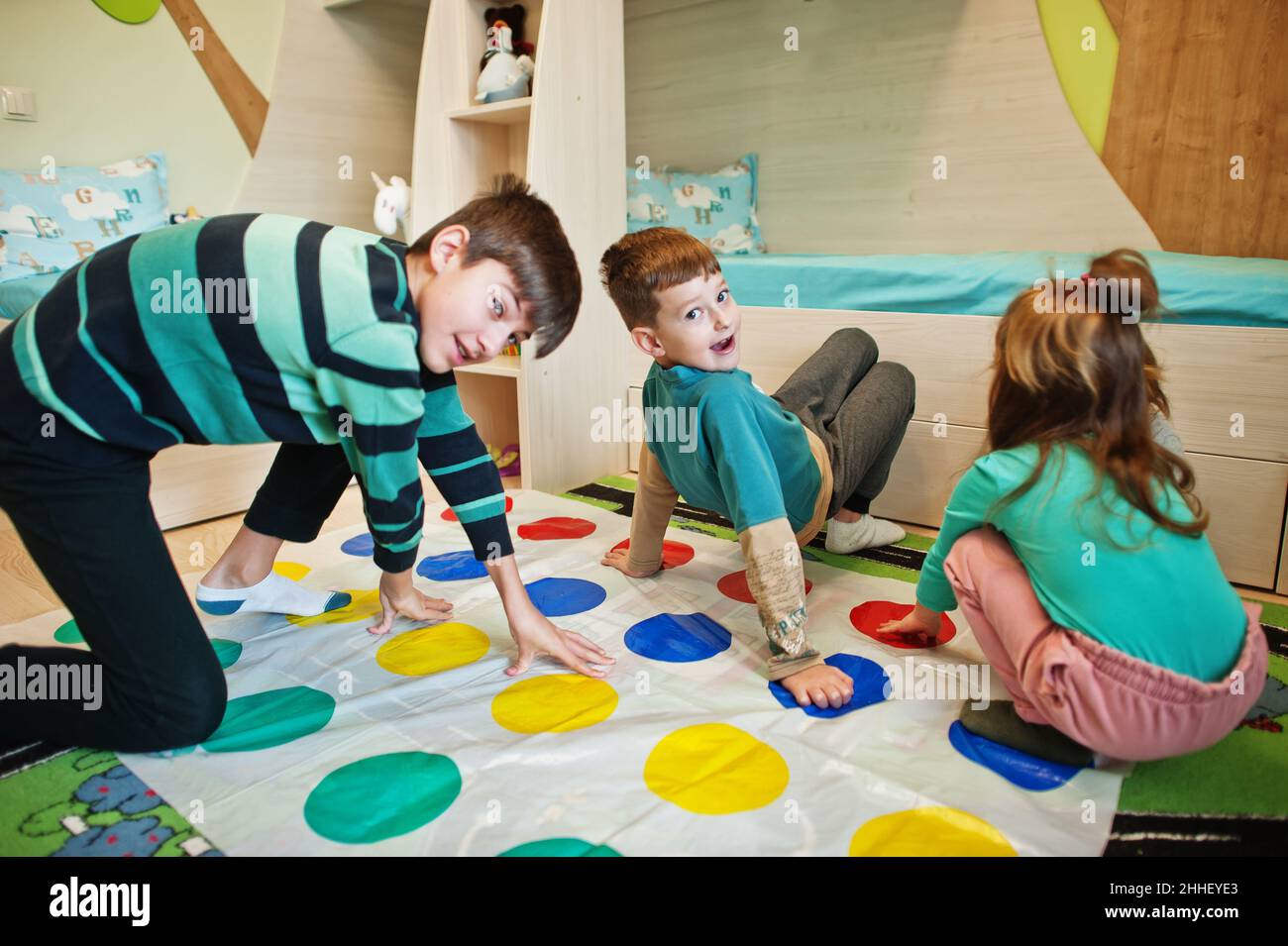 Happy family having fun together,four kids playing twister game at home. Stock Photo