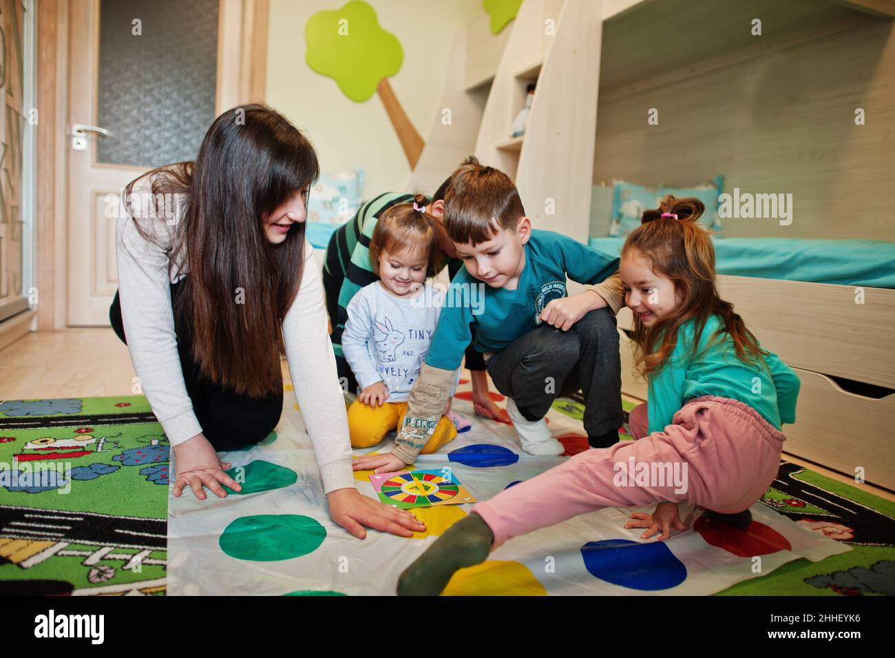 Happy family having fun together,four kids and mother playing twister game at home. Stock Photo