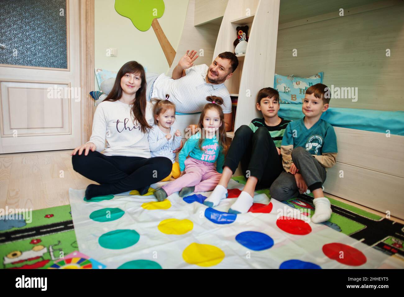 Happy big family having fun together,four kids playing twister game at home. Stock Photo